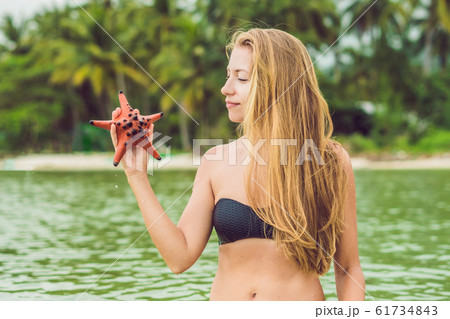 Young woman in the sea with red starfishes 61734843
