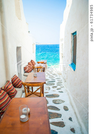 Benches with pillows in a typical greek outdoor cafe in Mykonos with amazing sea view on Cyclades islands 61734985