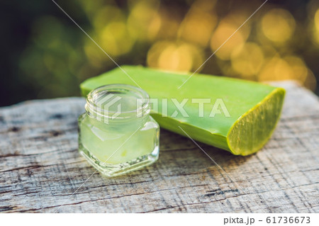 Slices of a aloe vera leaf and a bottle with transparent gel for medicinal purposes, skin treatment and cosmetics, close up 61736673