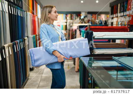Seller holds stack of fabric in textile store Seller holds stack of fabric in textile store 61737617