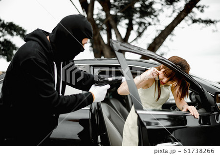 Bandit wear black mask using gun point to woman in black car and trying to rob money and hurting her 61738266