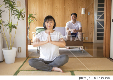 自宅でストレッチ　ヨガをする中年女性とそれを見守る旦那さん 61739390
