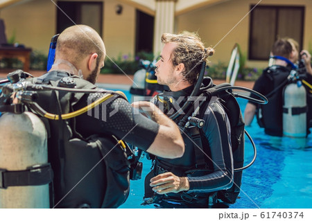 Diving instructor and students. Instructor teaches students to dive 61740374