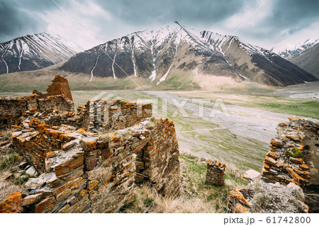 Fortress On Mountain Background Near Karatkau Village, Kazbegi District, Mtskheta-Mtianeti Region, Georgia. Spring, Summer Season. Truso Gorge. Fortress On Mountain Background Near Karatkau Village, Kazbegi District, Mtskheta-Mtianeti Region, Georgia. Spring, Summer Season. Truso Gorge. 61742800