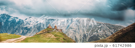 Stephantsminda, Georgia. Gergeti Trinity Church Or Tsminda Sameba - Holy Trinity Church Near Village Of Gergeti In Georgia. Panoramic View At Spring Sunny Day 61742986