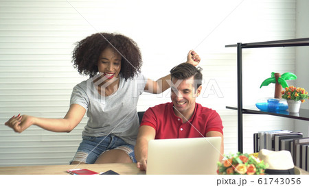 Happy Multi ethnic couple looking for Summer deal on internet Happy Multi ethnic couple looking for Summer deal on internet 61743056