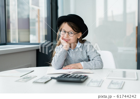 Little smiling accountant looking at you while counting salary by workplace 61744242