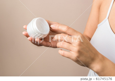 closeup view of woman hands holding a white jar and applying cream closeup view of woman hands holding a white jar and applying cream 61745176