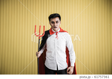 Young Asian man in costume dracula on yellow 61757361