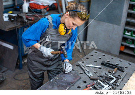 Sideview of worker woman marking piece of metal Sideview of worker woman marking piece of metal 61763552