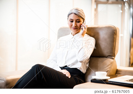 Company boss in the armchair with coffee and phone stock photo 61767005