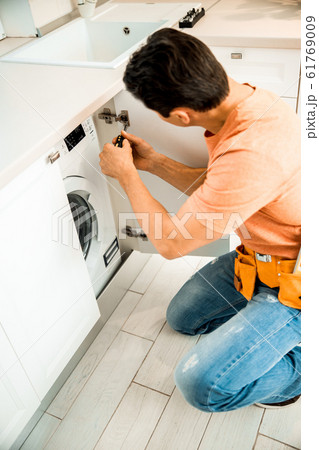 Worker with belt repairing furniture on the kitchen 61769009