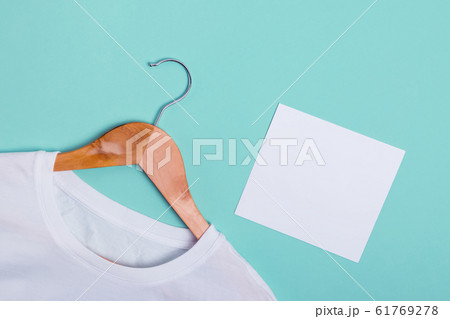 White t-shirt lying on green turquoise background and blank paper card 61769278
