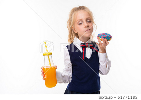 Pretty schoolgirl eats a donut and drinks juice isolated on white background Pretty schoolgirl eats a donut and drinks juice isolated on white background 61771185