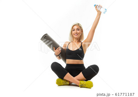 Caucasian sport woman with blonde hair sits with sports mat and smiles 61771187