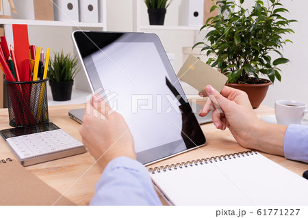 a man works with a tablet and do notes on his desktop with calculator, pens, pencils, card, phone 61771227