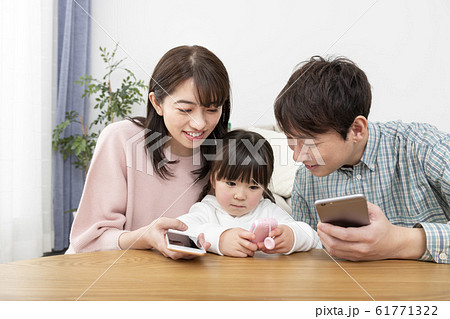スマートフォンを持つ両親とキッズケータイを持つ女の子　家族イメージ 61771322