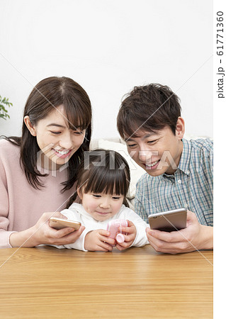 スマートフォンを持つ両親とキッズケータイを持つ女の子 家族イメージ スマートフォンを持つ両親とキッズケータイを持つ女の子 家族イメージ 61771360