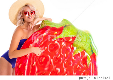 Pretty blonde caucasian female stands in swimsuit with rubber beach mattress and smiles isolated on 61771421