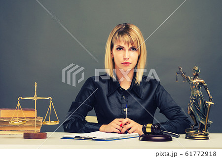 A young fair woman judge works in her office. A young fair woman judge works in her office. 61772918
