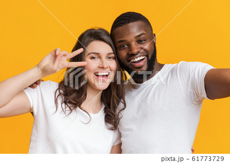 Joyful two international friends taking selfie together and showing peace sign Joyful two international friends taking selfie together and showing peace sign 61773729