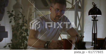 Artist drawing at table Artist drawing at table 61777605