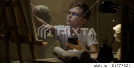 Boy using smartphone and drawing Boy using smartphone and drawing 61777629