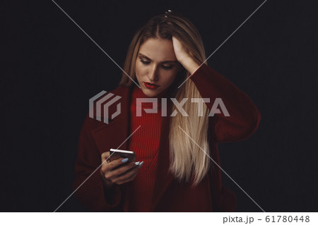 Sad woman in stress with phone isolated in the dark room. 61780448