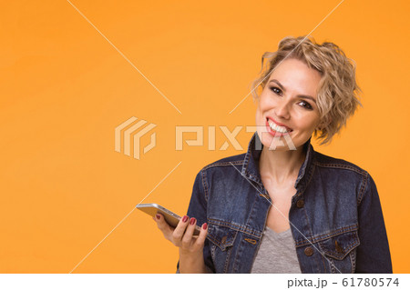Fashion pretty woman using smartphone in rock black style over colorful orange background 61780574