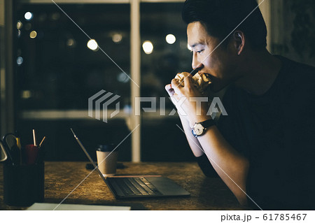 仕事をしながらご飯を食べる男性 61785467