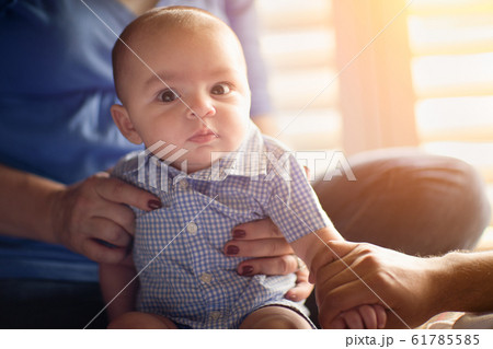 Happy Mixed Race Couple Enjoying Their Newborn Son In The Light of The Window. 61785585