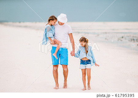 Happy beautiful family of dad and kids on white beach Happy beautiful family of dad and kids on white beach 61795395