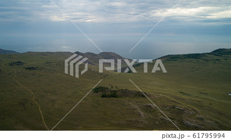 Baikal region. Dirt road on Tazheranskaya steppe near the stone rocks, called the Valley of the Stone Spirits. Aerial 61795994