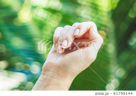 Broken nail on a woman's hand with a manicure on a green background Broken nail on a woman's hand with a manicure on a green background 61799144