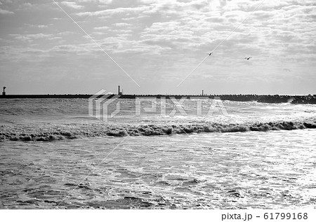 千葉県 いすみ市 大原町 大原海岸 白波と防波堤で釣りをする人々の影 12月の海の風景 白黒 の写真素材