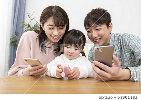 スマートフォンを持つ両親とキッズケータイを持つ女の子　家族イメージ 61801183