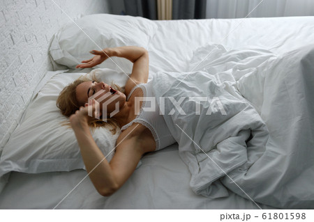 Young woman awakening and stretching in comfortable cozy bed. Young woman awakening and stretching in comfortable cozy bed. 61801598