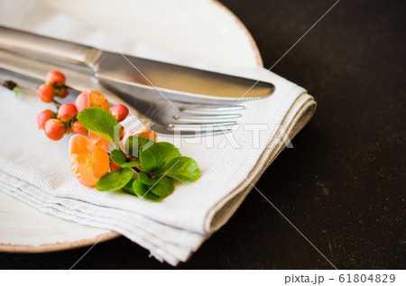 Vintage table setting with delicate flowers on a linen napkin on a dark background, close-up 61804829
