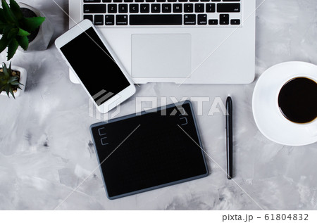 Flat lay photography of creative desk. Overhead view of graphic tablet, graphic pen, smartphone, laptop and a cup of black coffee.  61804832