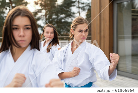 Group of young women practising karate outdoors on terrace. 61806964
