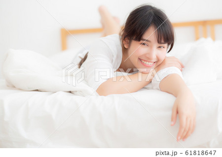 Beautiful portrait young asian woman lying and smile while wake up with sunrise at morning 61818647