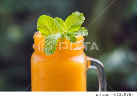 Mango smoothie in a glass Mason jar and mango on a green background. Mango shake. Tropical fruit concept 61820867