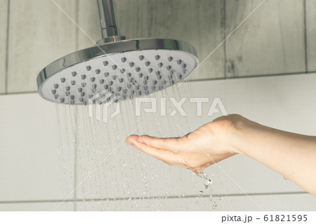 Female hand touching water pouring from a rain shower head, checking water temperature Female hand touching water pouring from a rain shower head, checking water temperature 61821595