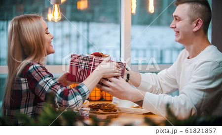 A young couple in cafe - a man gives his girlfriend a christmas gift 61821857