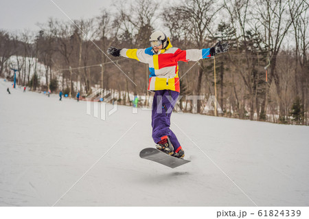 Young man jumping with a snowboard in the mountains Young man jumping with a snowboard in the mountains 61824339