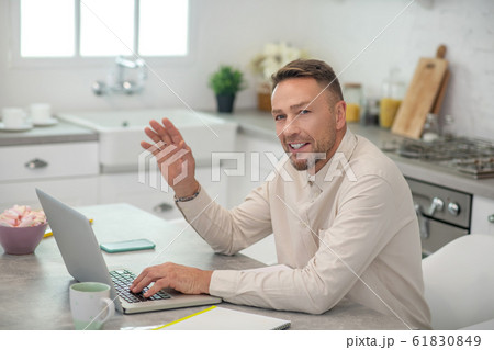 Good-looking bearded man sitting in the kitchen and waving his hand 61830849