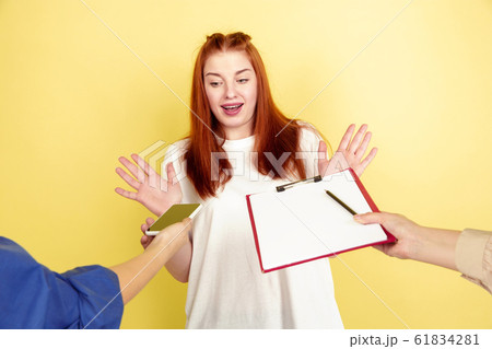 Caucasian young woman's portrait on yellow background, too much tasks 61834281