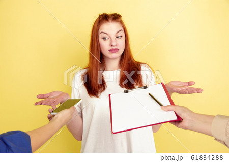 Caucasian young woman's portrait on yellow background, too much tasks 61834288