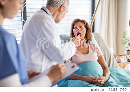 Senior male doctor examining a woman patient in hospital. 61834746