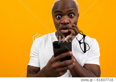 beautiful dark-skinned American student with white hair looks thoughtfully on the phone in his hands 61837718